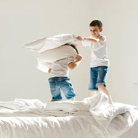 Una imagen de dos niños en una pelea de almohadas