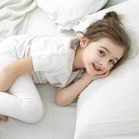 Una imagen de una niña descansando sobre una gran almohada