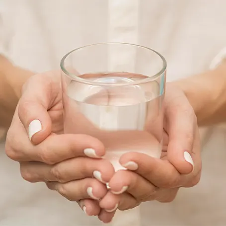 Imagen de una mujer con un vaso de agua en la mano.