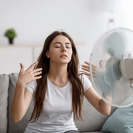 Una imagen de una mujer refrescándose apuntándose con un ventilador