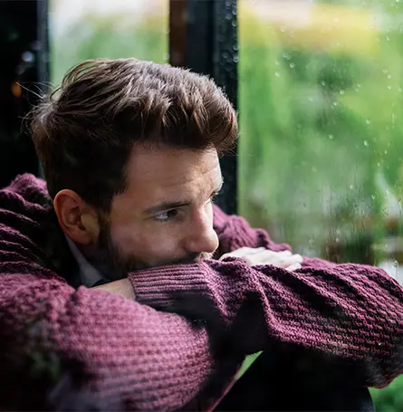 Imagen de un hombre con TAS mirando por la ventana